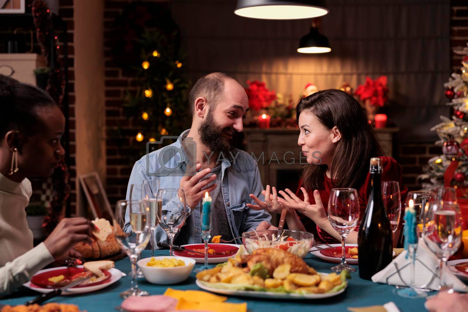 Royalty free image of Couple chatting at family christmas home party by DCStudio