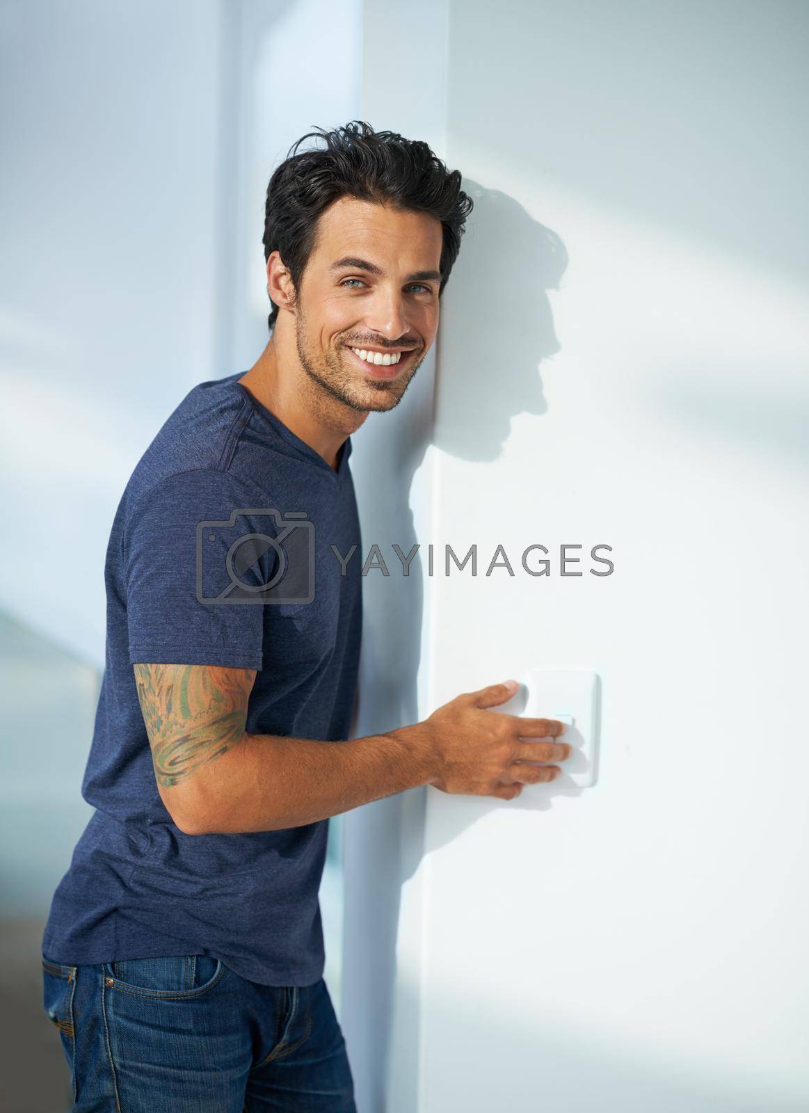 Royalty free image of Hes eco conscious - turning of his lights. Portrait of a handsome young man smiling and pressing a light switch. by YuriArcurs