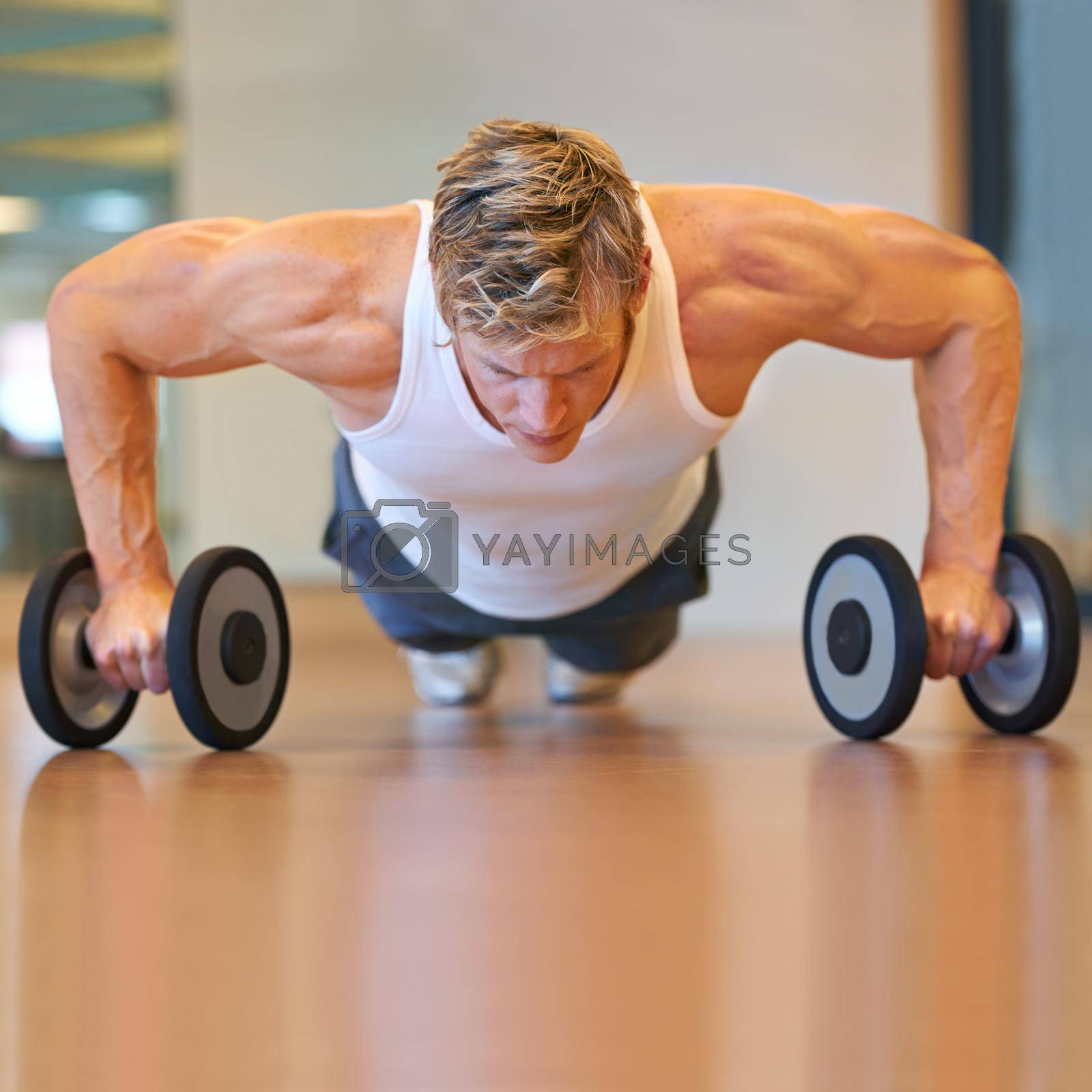 Royalty free image of Doing some push-ups. Fit young man doing push ups in a health club using dumbbells. by YuriArcurs