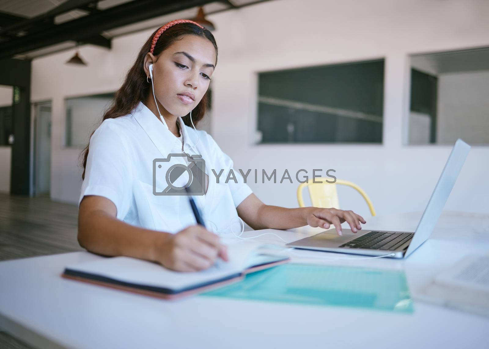 Royalty free image of Planning, writing and business woman working on a laptop and write notes while listening to online seminar in office. Startup, marketing and lady business owner search for creative advertising tips by YuriArcurs