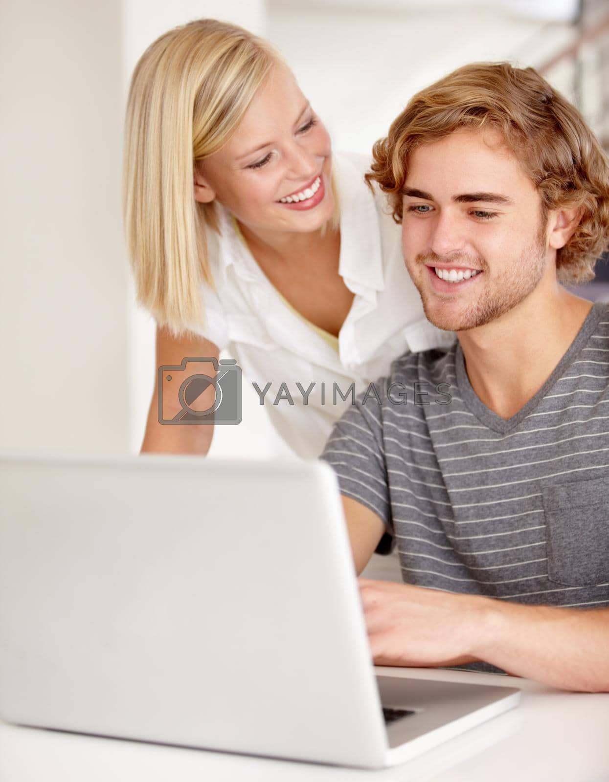 Royalty free image of Wow, your website is impressive. A happy young couple using a laptop indoors. by YuriArcurs