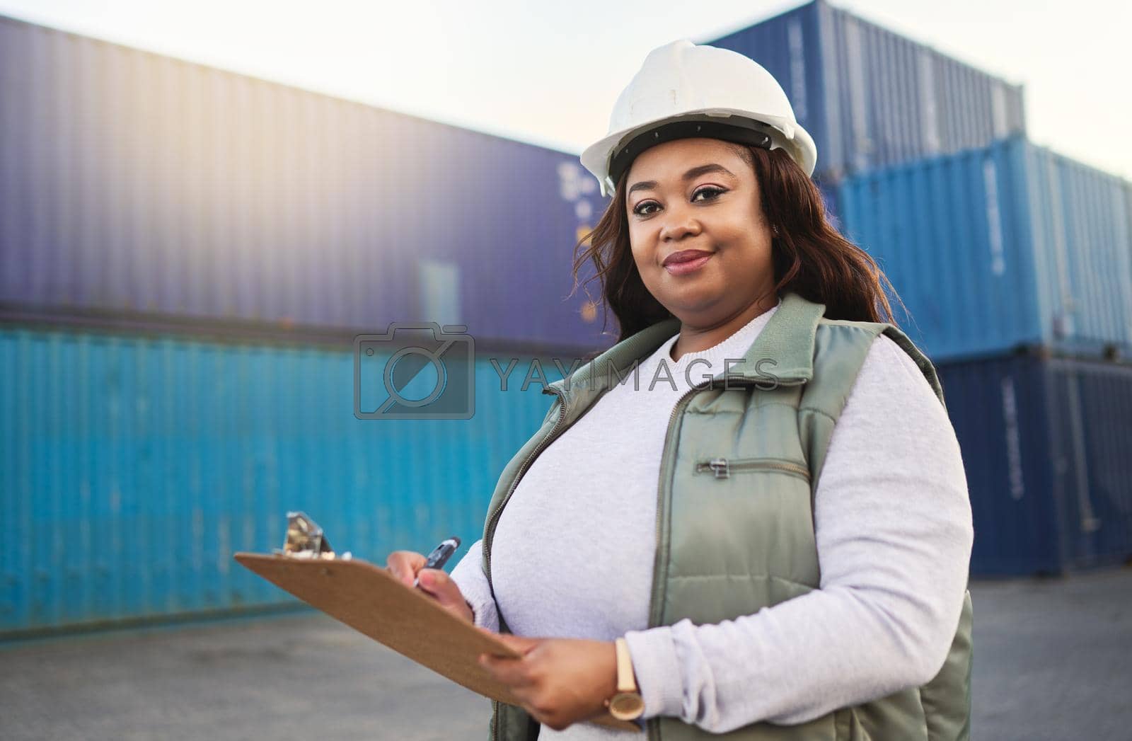 Royalty free image of Logistics, supply chain and shipping with a delivery woman working on a dock with documents on a clipboard and a container yard in the background. Stock, cargo and freight with a female export worker by YuriArcurs