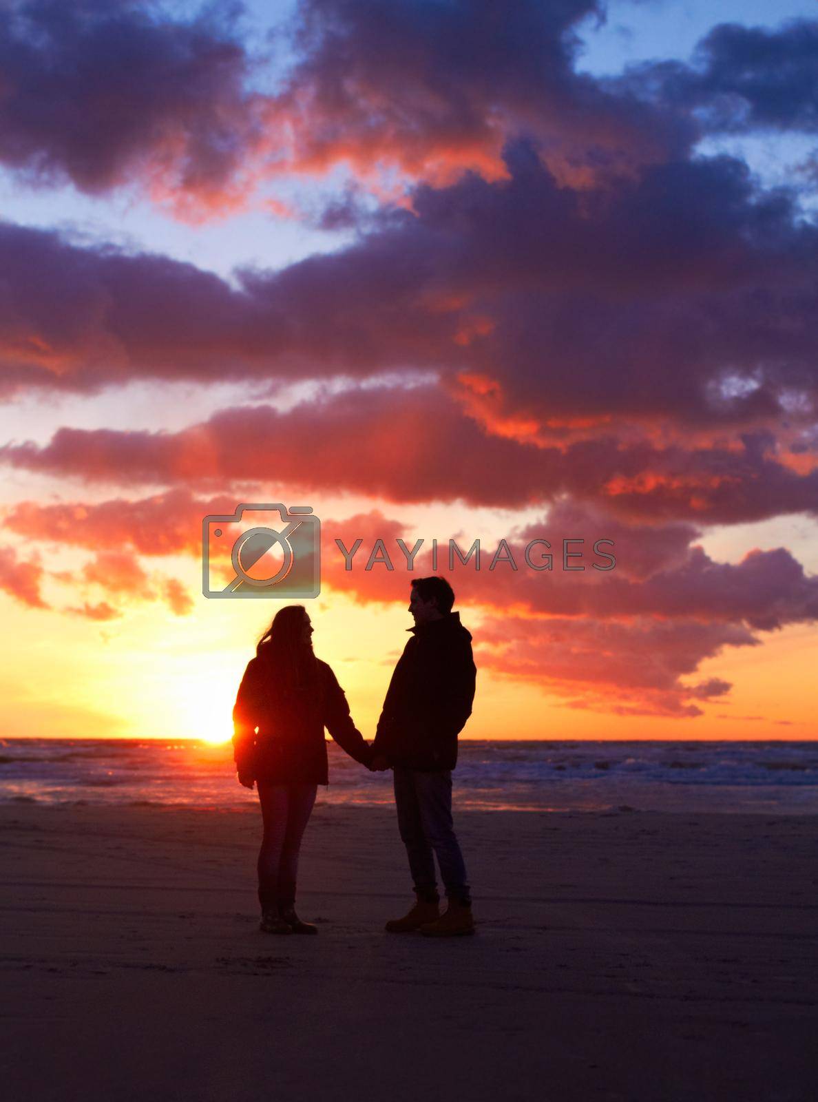 Romance after dark. Silhouette of a couple going for a walk on the beach at sunset