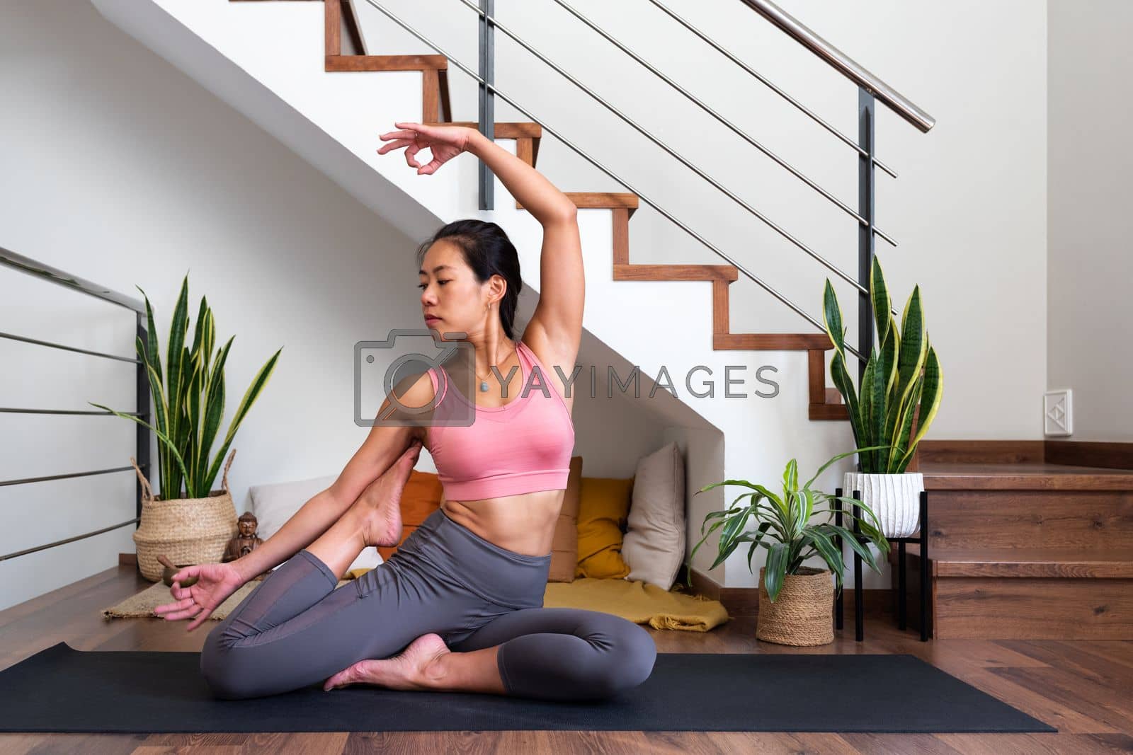 Royalty free image of Young flexible Asian woman doing beautiful yoga asana at home living room. Healthy lifestyle by Hoverstock