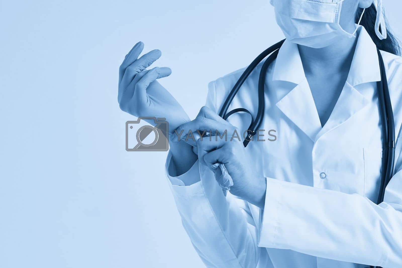 Royalty free image of Young doctor putting on surgical gloves over white background by Mariakray