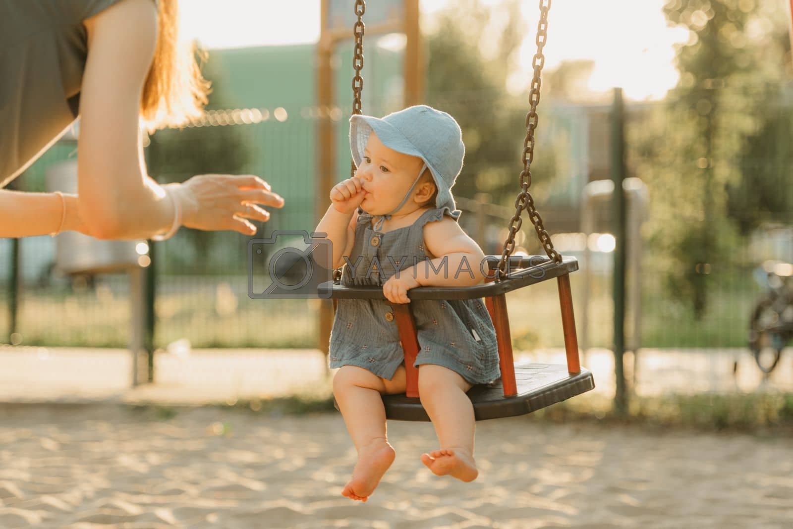 Royalty free image of Toddler baby girl on a swing is sucking her thumb on the warm summer evening by RomanJRoyce