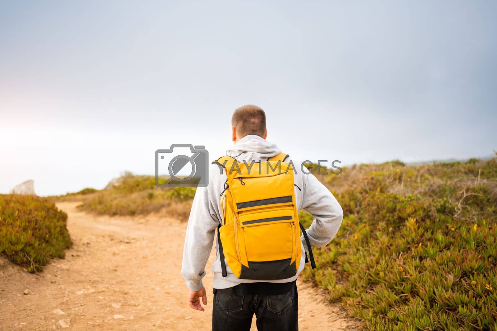 Royalty free image of Rear-view young man traveler with yellow backpack by andreonegin
