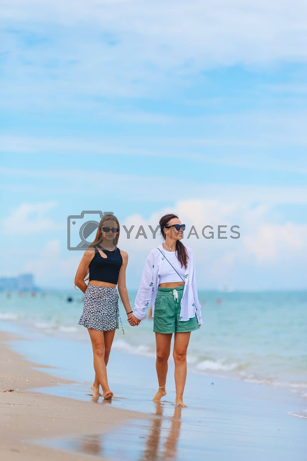 Royalty free image of Beautiful mother and her teen daughter on the beach by travnikovstudio