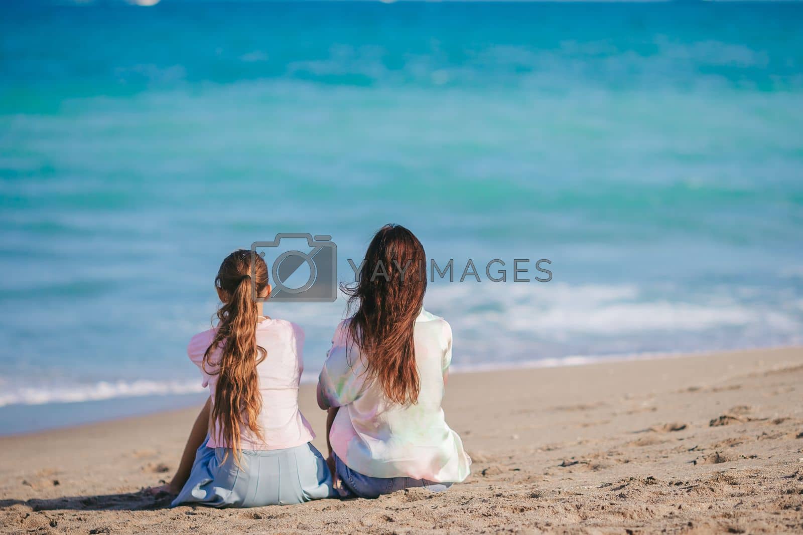Royalty free image of Beautiful mother and her teen daughter on the beach by travnikovstudio