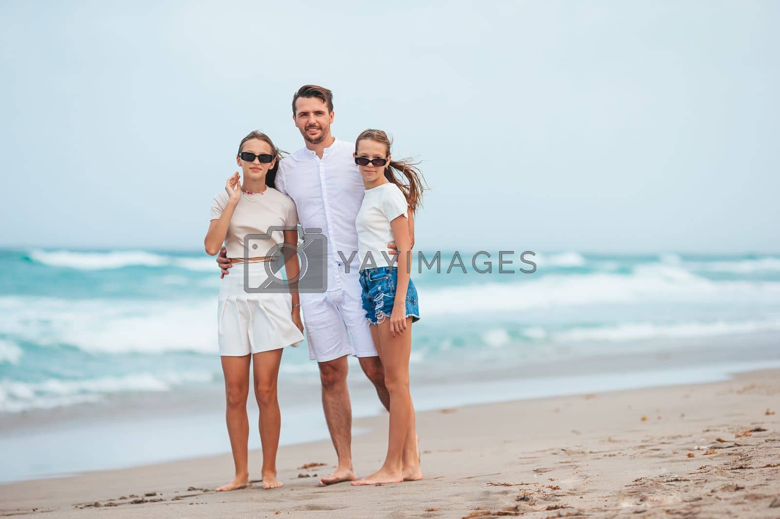 Royalty free image of Young father and his adorable teen daughters on the beach. Family vacation by travnikovstudio