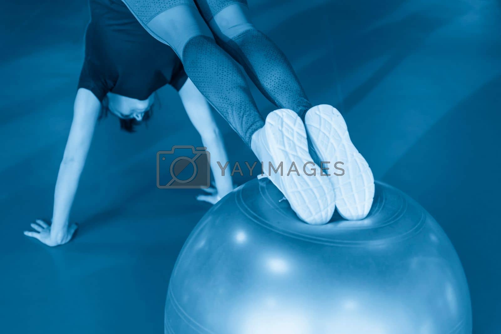 Royalty free image of Woman at the gym doing exercises with her legs on pilates ball by Mariakray