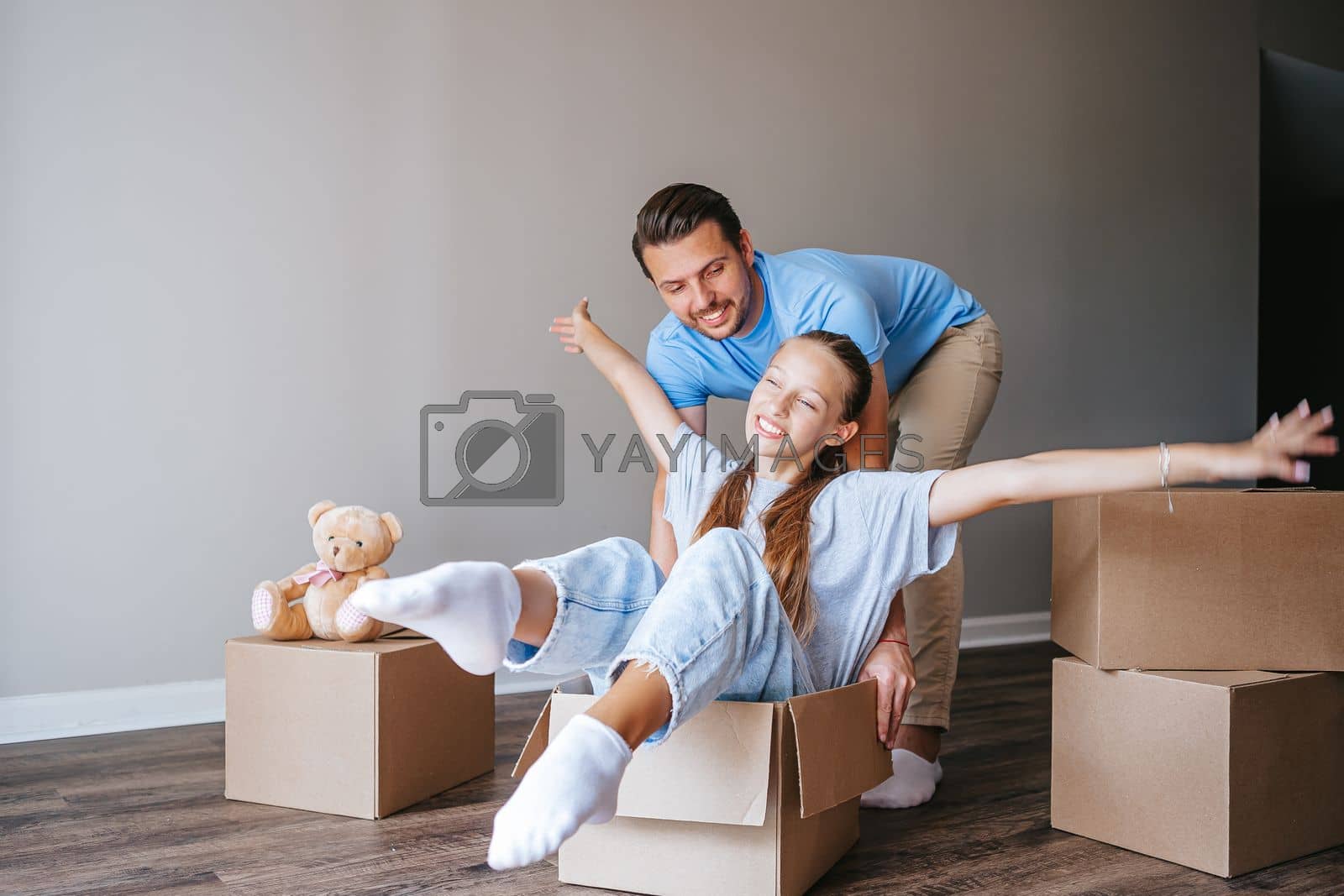 Royalty free image of Family of father and adorable teen daughter have fun on moving day in their new home by travnikovstudio