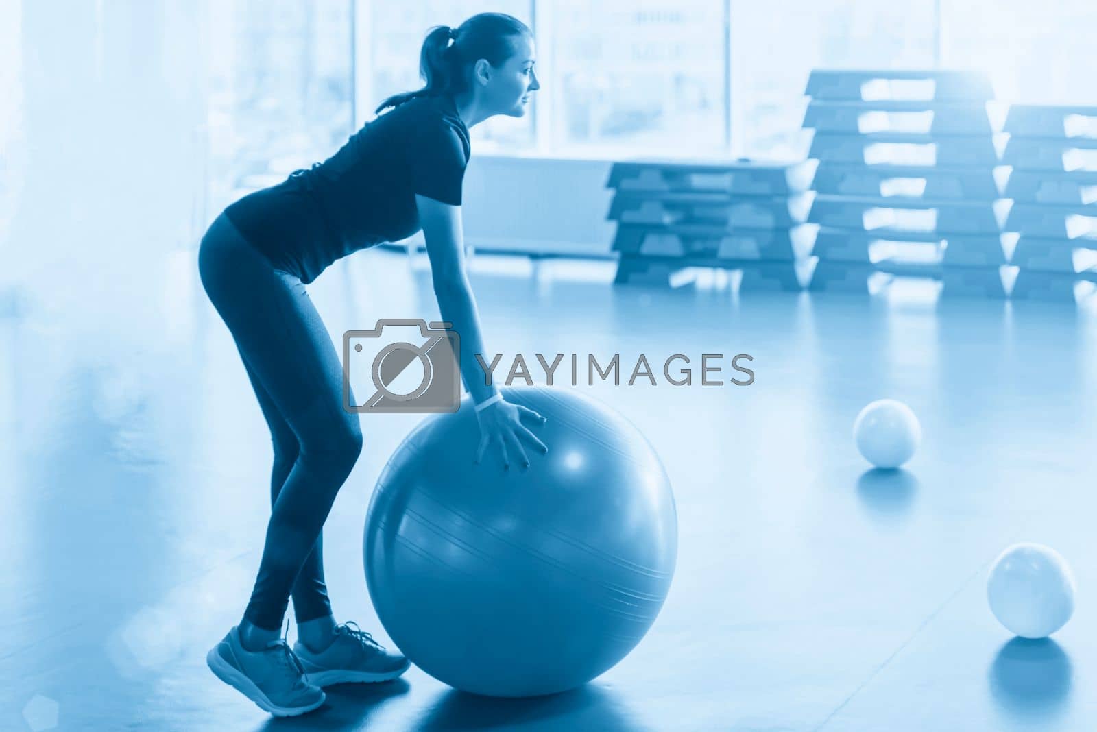 Royalty free image of Woman at the gym doing exercises with pilates ball by Mariakray