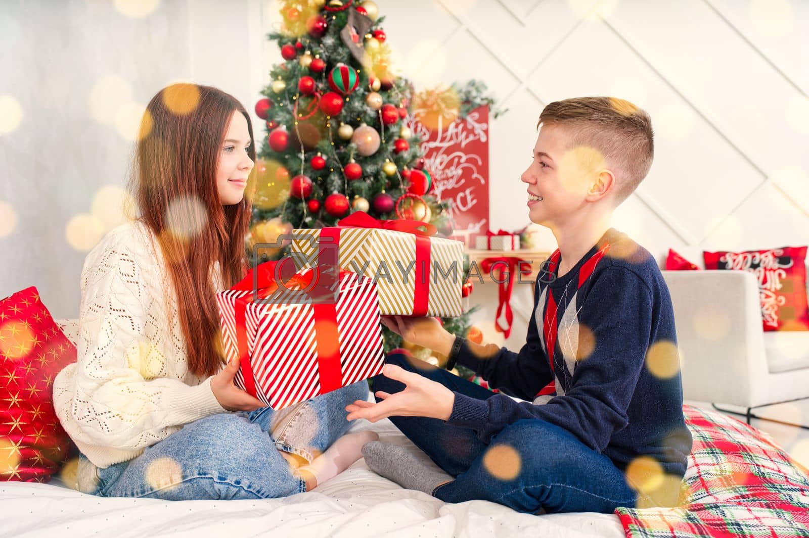 Royalty free image of A cheerful teenagers opens a Christmas gifts. Cheerful Teenagers lies in bed with a christmas presents in they hands by PhotoTime