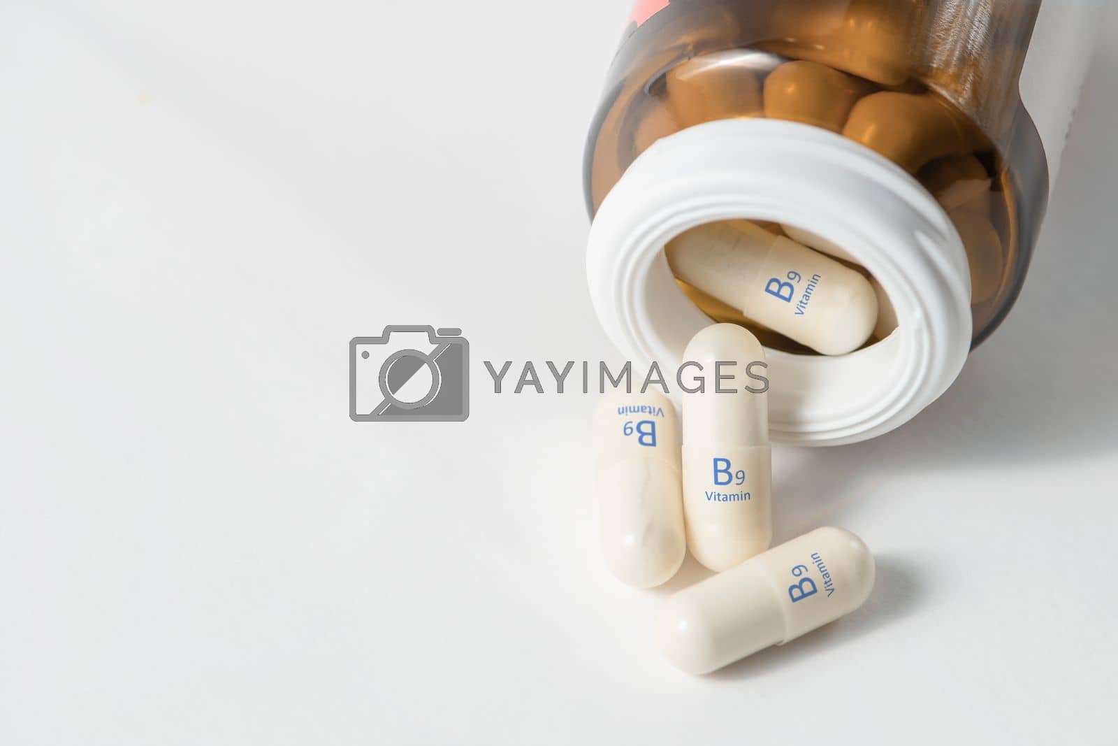 Royalty free image of Vitamin B9. Capsules with folic acid, necessary for the growth and development of the circulatory and immune systems. White capsules of vitamin B9 or folic acid are scattered with copy space. by SERSOL