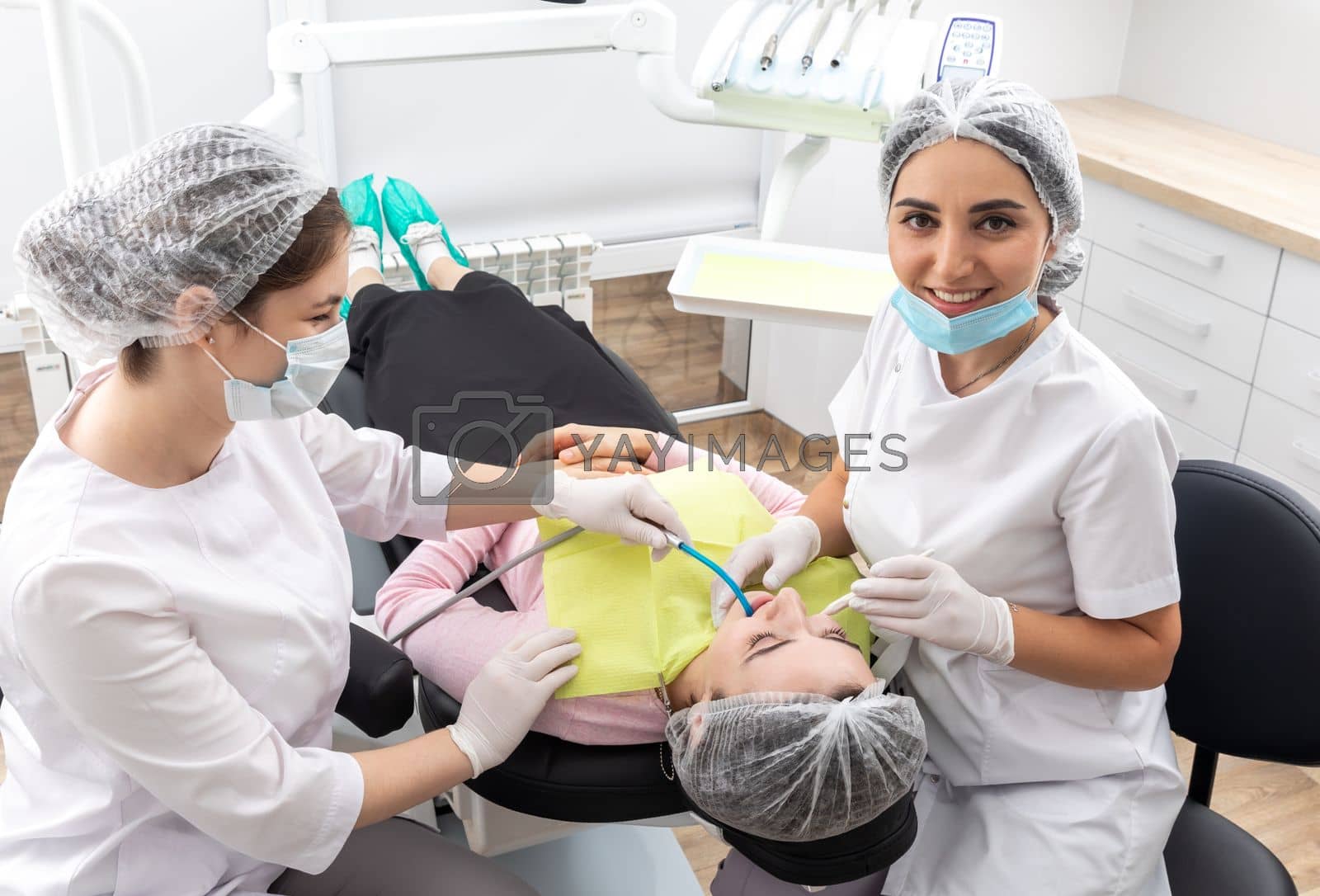 Royalty free image of Dentist and assistant performing dental treatment inmodern dental clinic, patient laying in a chair by Mariakray