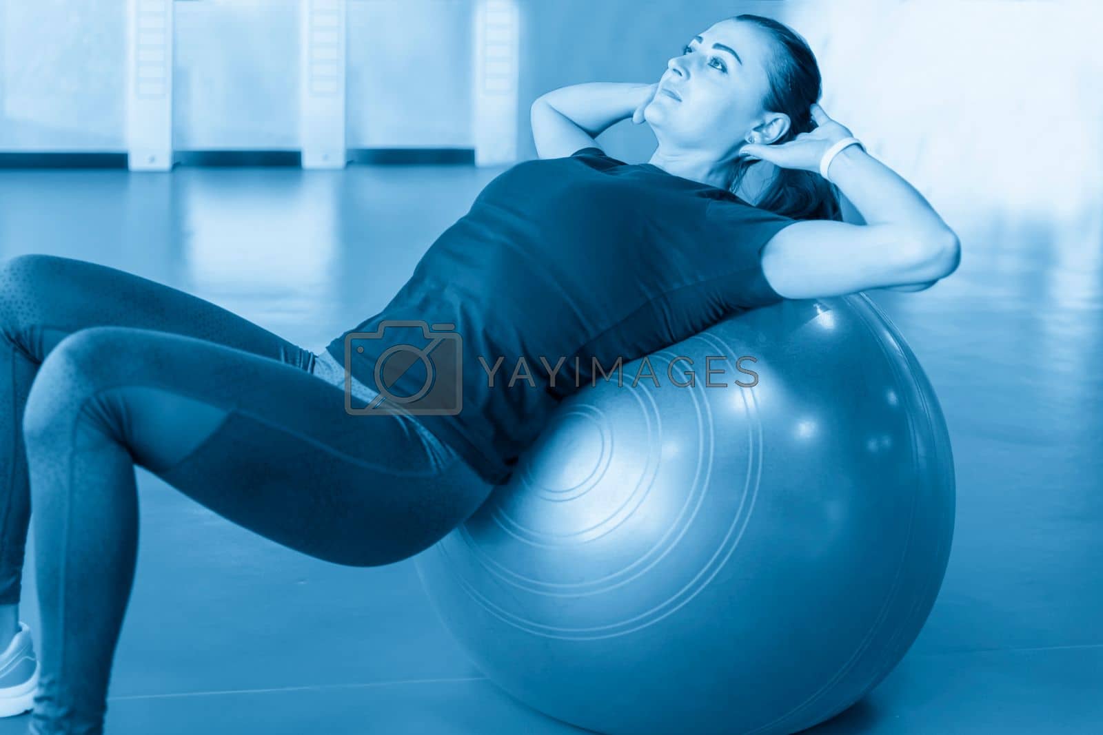 Royalty free image of Woman at the gym doing exercises with pilates ball on her back by Mariakray