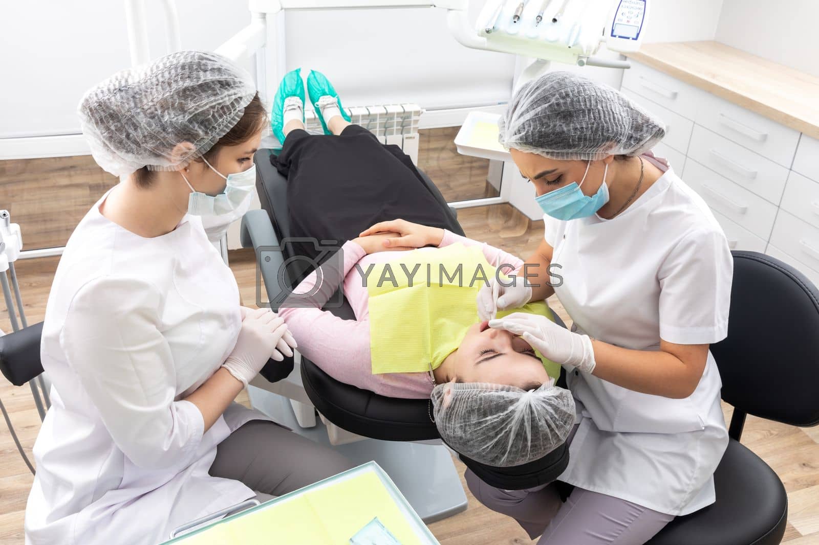 Royalty free image of Professional dentist surgeon and assistant performing dental operation in a clinic with modern equipment by Mariakray