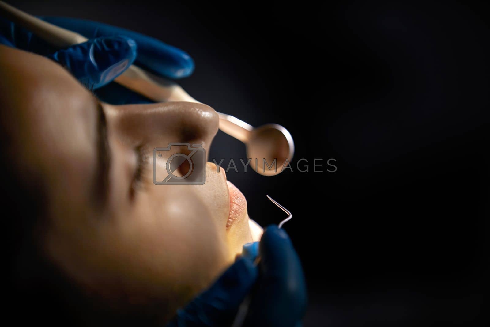 Royalty free image of Dentist checking teeth of a female patient with dental mirror by Mariakray
