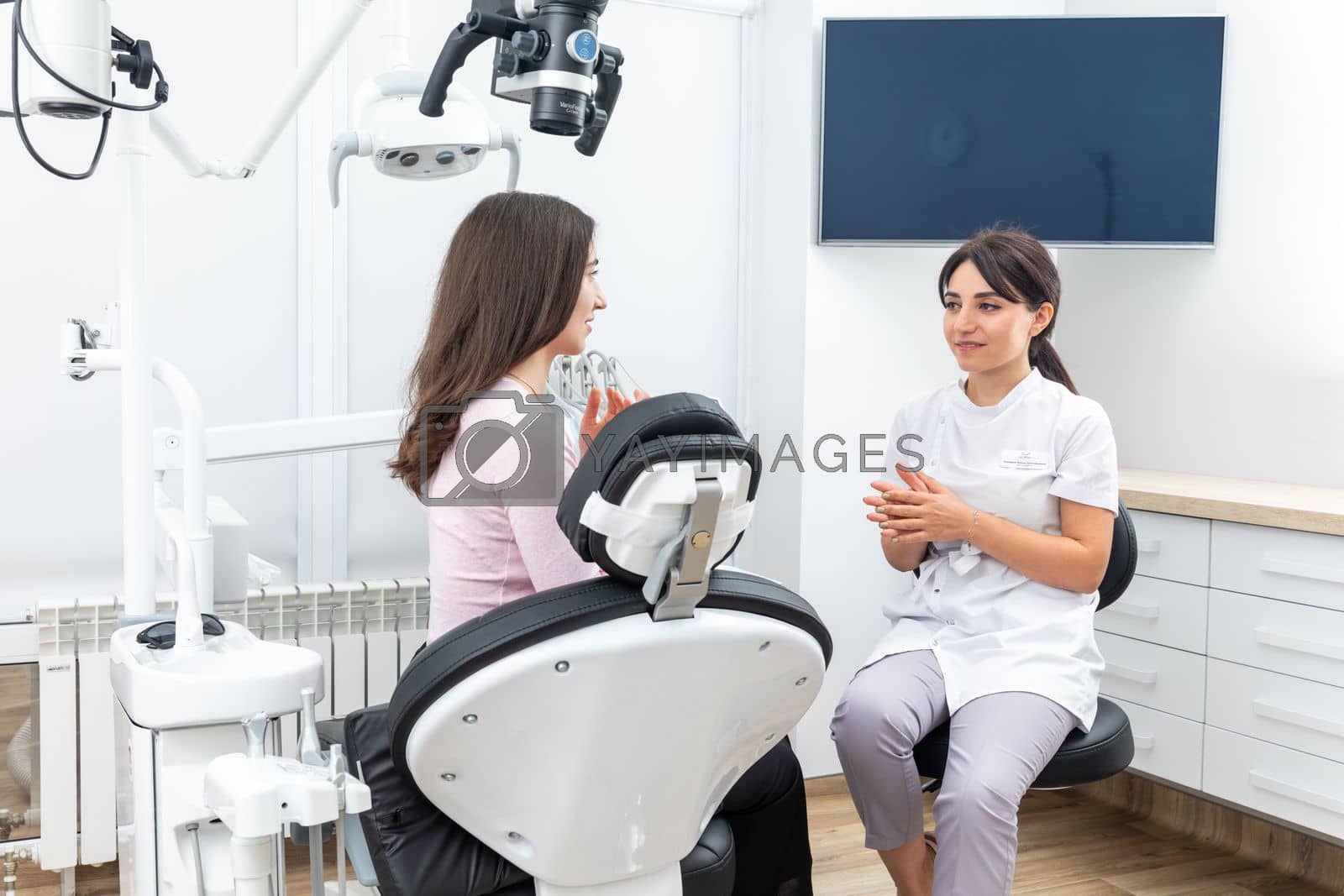 Royalty free image of Female dentist explaining patient treatment during an appointment in dental clinic by Mariakray