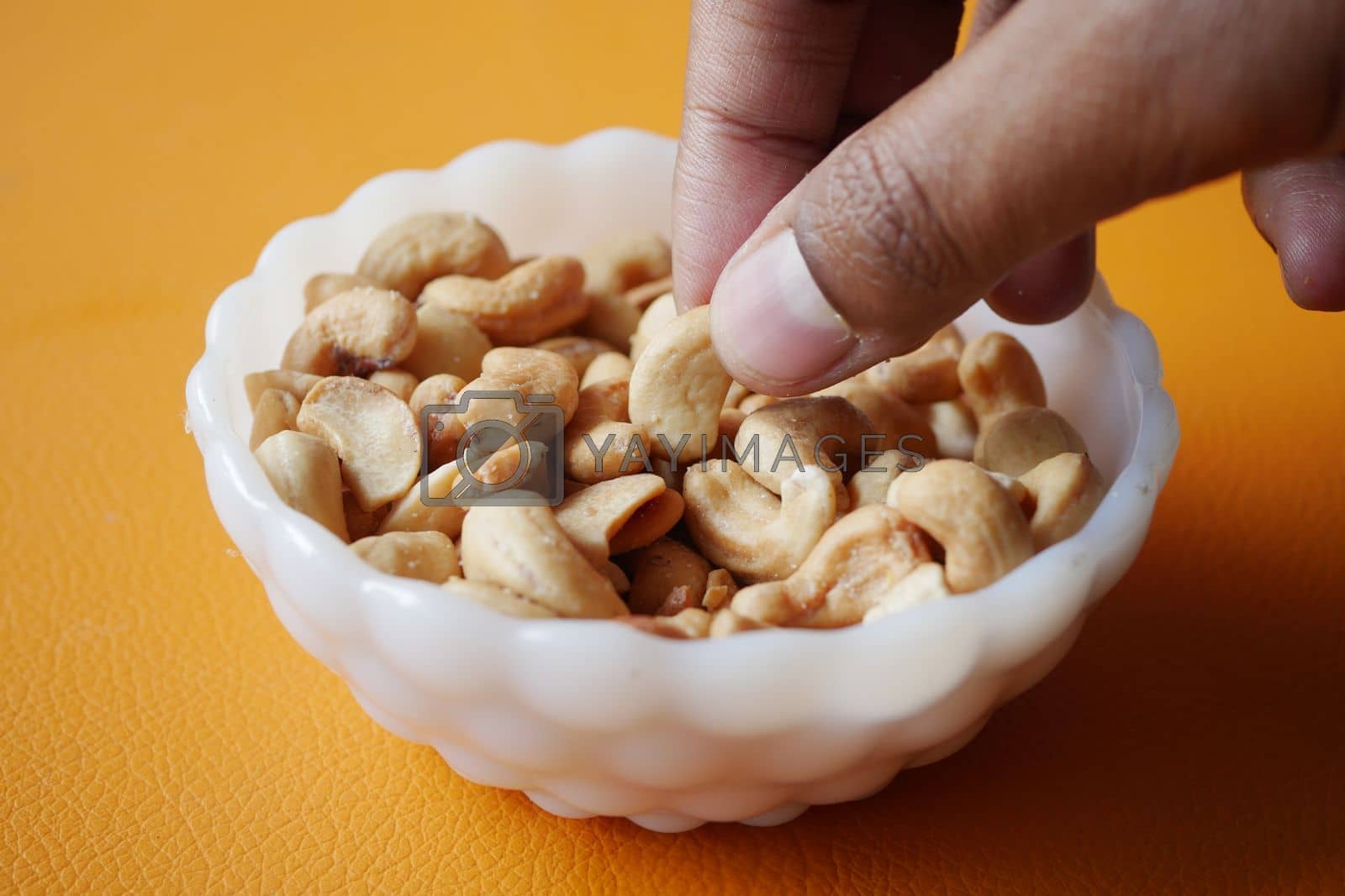 Royalty free image of hand pick a cashew nut from a small bowl by towfiq007