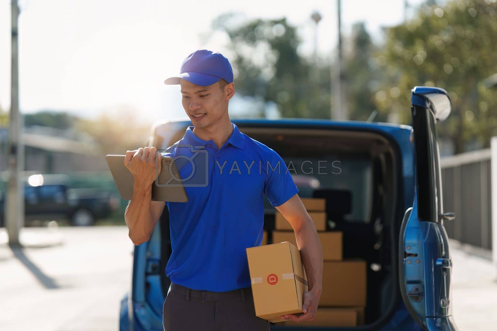 Royalty free image of Asian courier with parcel and delivery logistic concept. Delivery man using digital tablet by itchaznong
