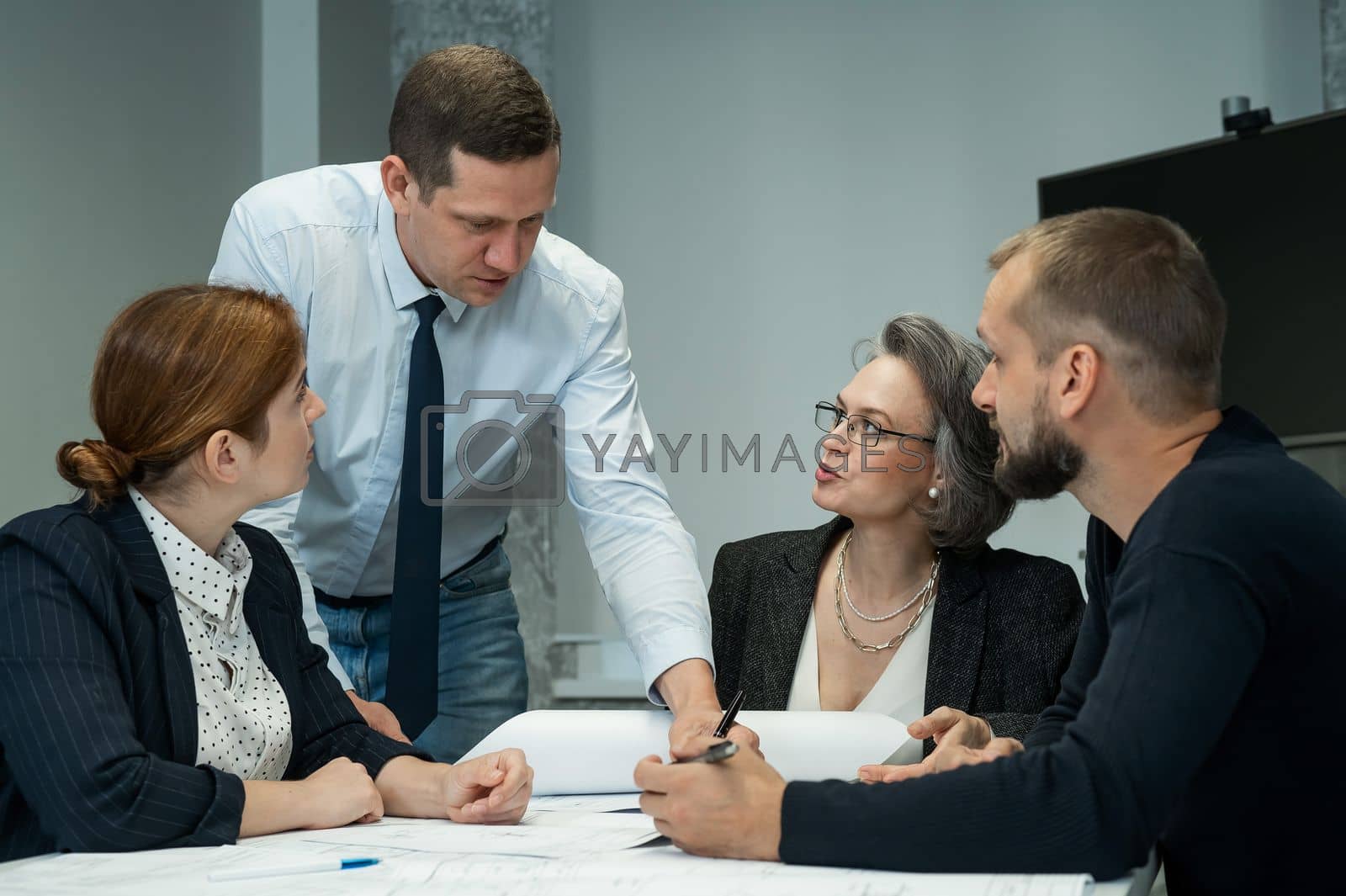 Royalty free image of The boss gives instructions to three employees in the office conference room. Brainstorming engineers and architects. by mrwed54