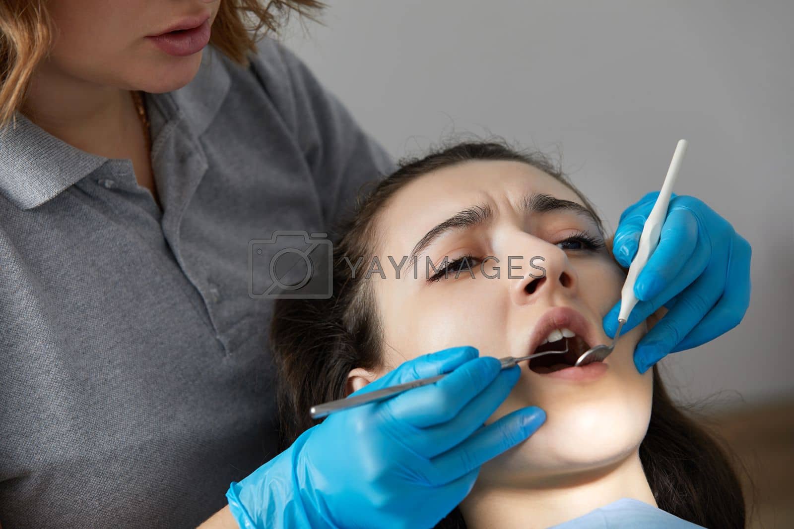 Royalty free image of Dentist checking teeth of a female patient with dental mirror by Mariakray