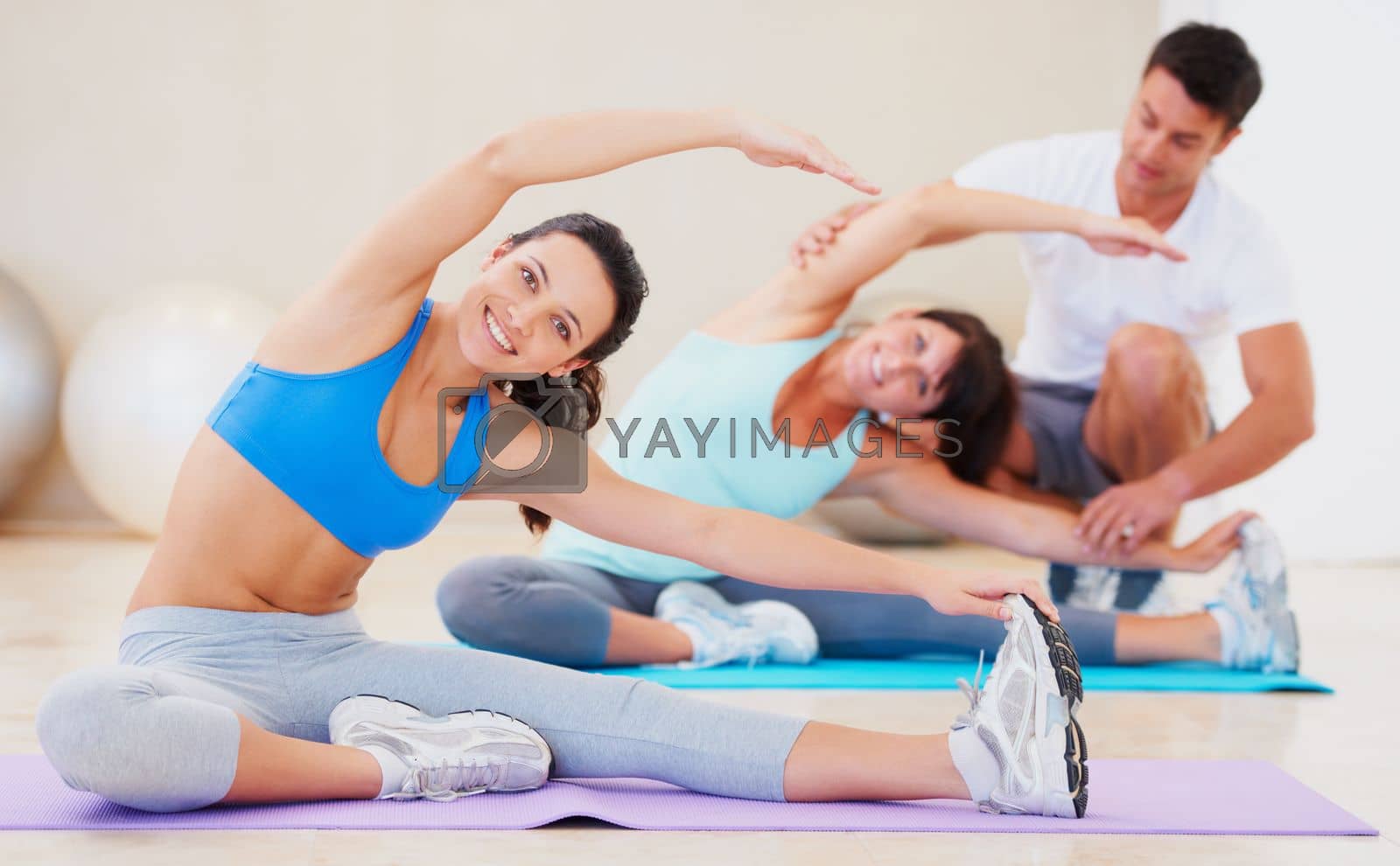 Royalty free image of She believes in regular exercise. Young woman doing a pilates class with the help of an instructor. by YuriArcurs