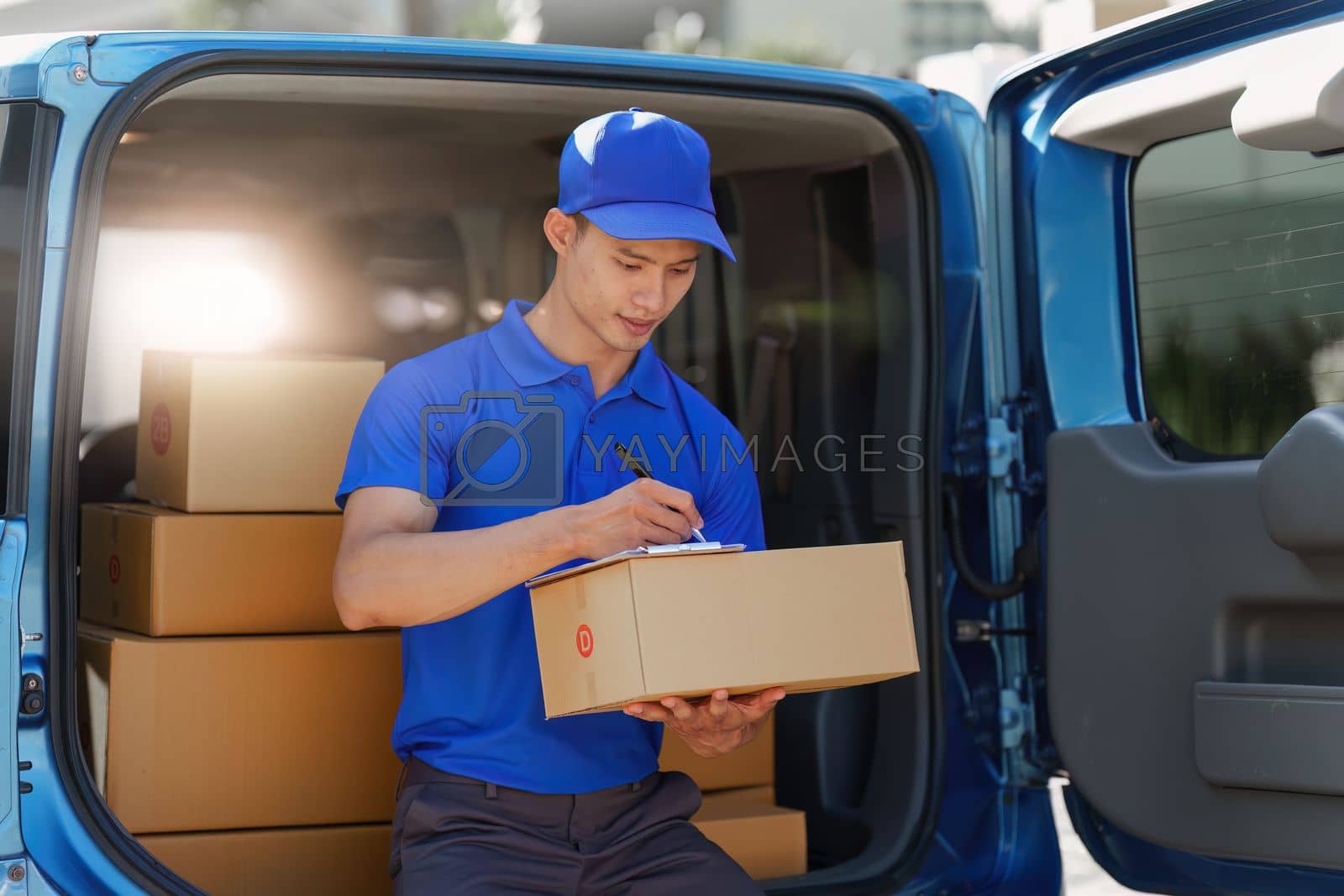 Royalty free image of Asian courier with parcel and delivery logistic concept. Delivery man using digital tablet by itchaznong