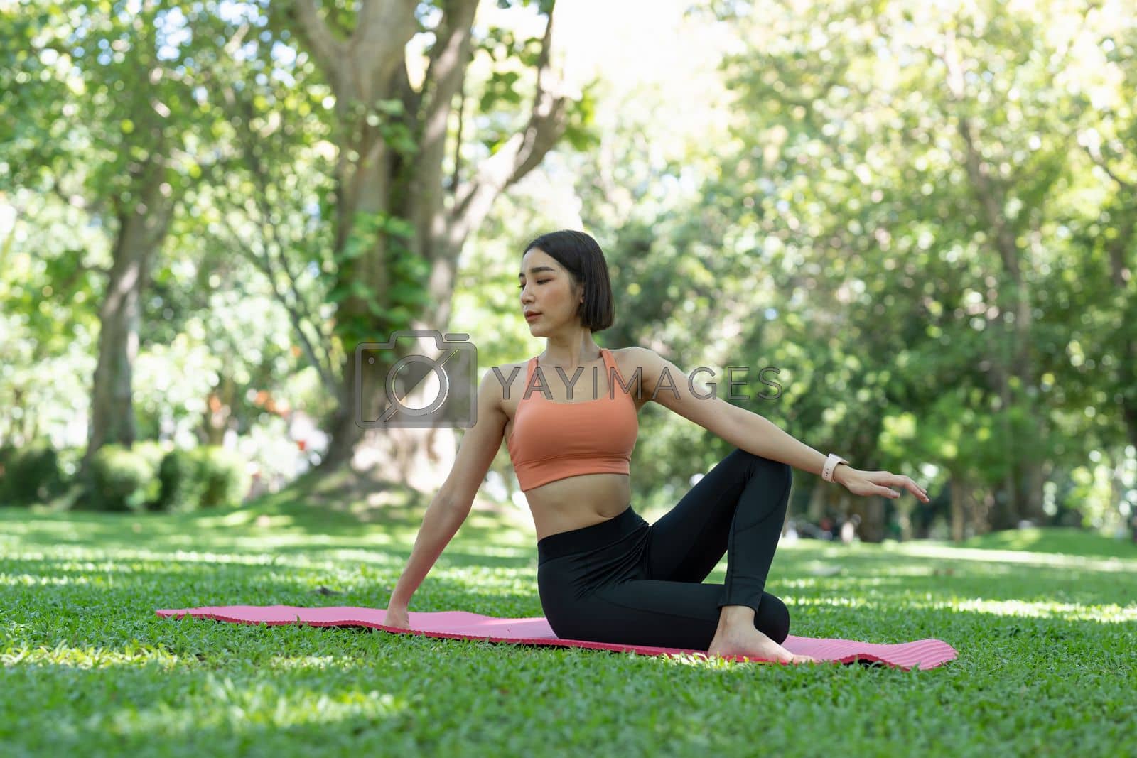 Royalty free image of Young attractive girl is doing advanced yoga asana on the fitness mat in the middle of a park. by nateemee