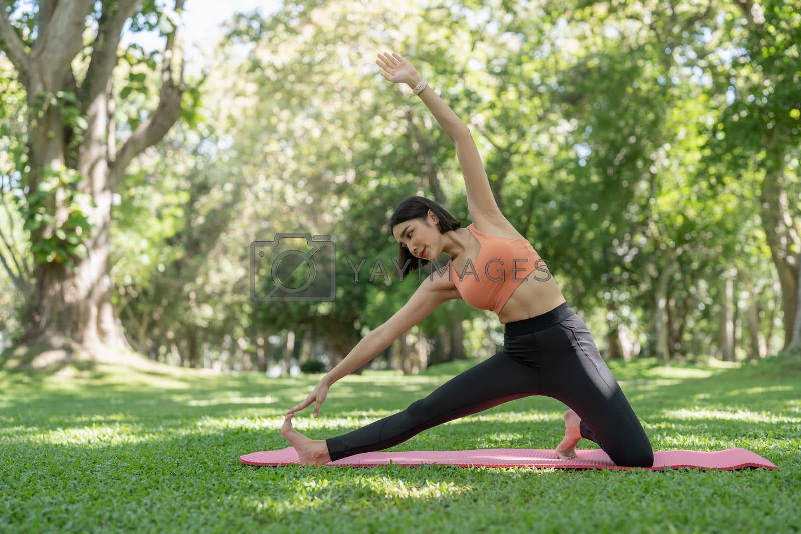 Royalty free image of Young attractive girl is doing advanced yoga asana on the fitness mat in the middle of a park. by nateemee