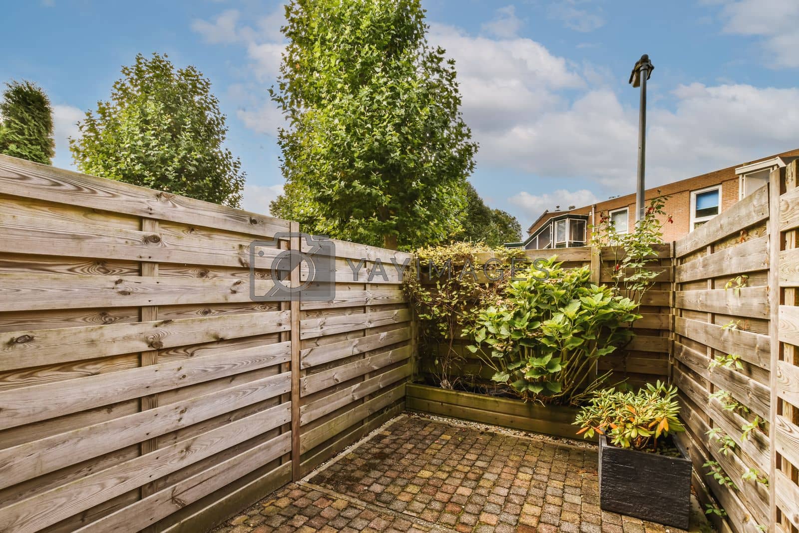 Royalty free image of a backyard with a wooden fence and a brick patio by casamedia