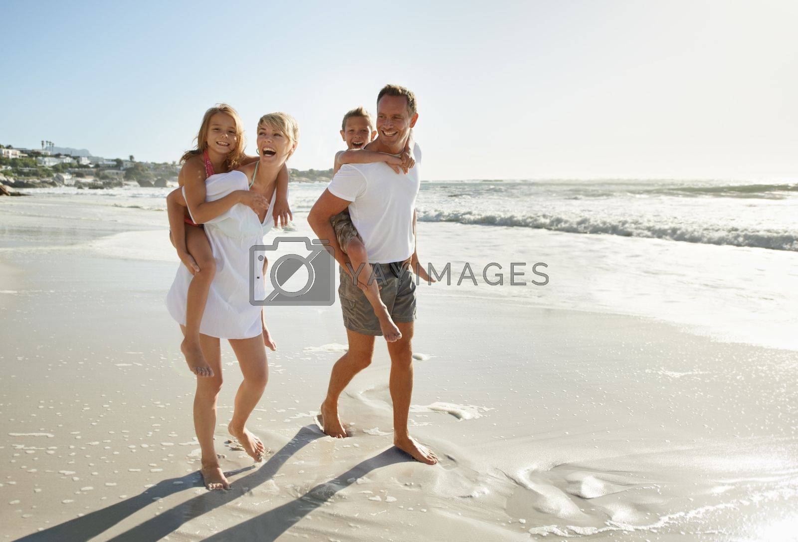 Royalty free image of Taking a family beach stroll. Smiling parents carrying their son and daughter down the beach. by YuriArcurs