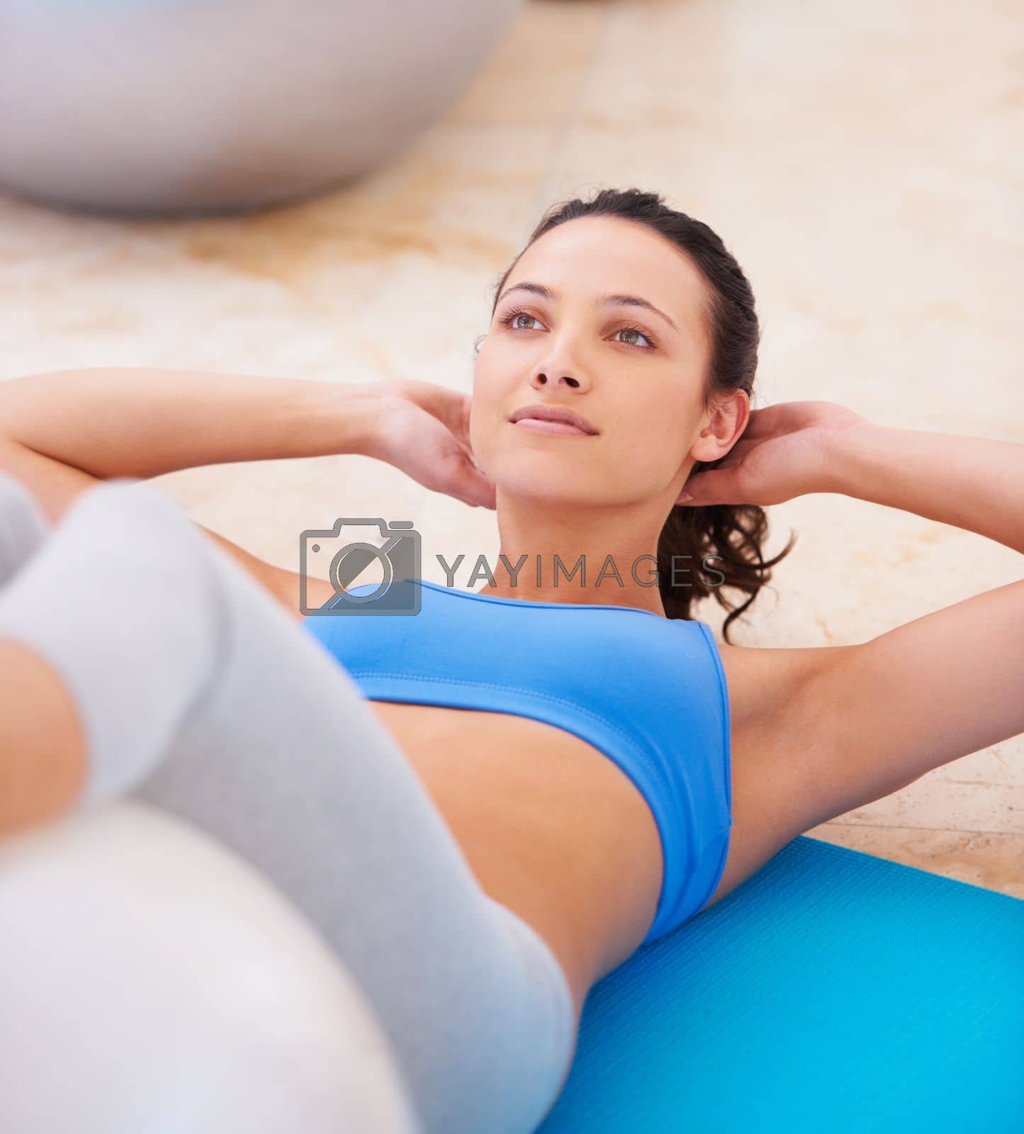 Royalty free image of Working towards a toned midriff. Fit woman doing a sit up during a pilates class. by YuriArcurs