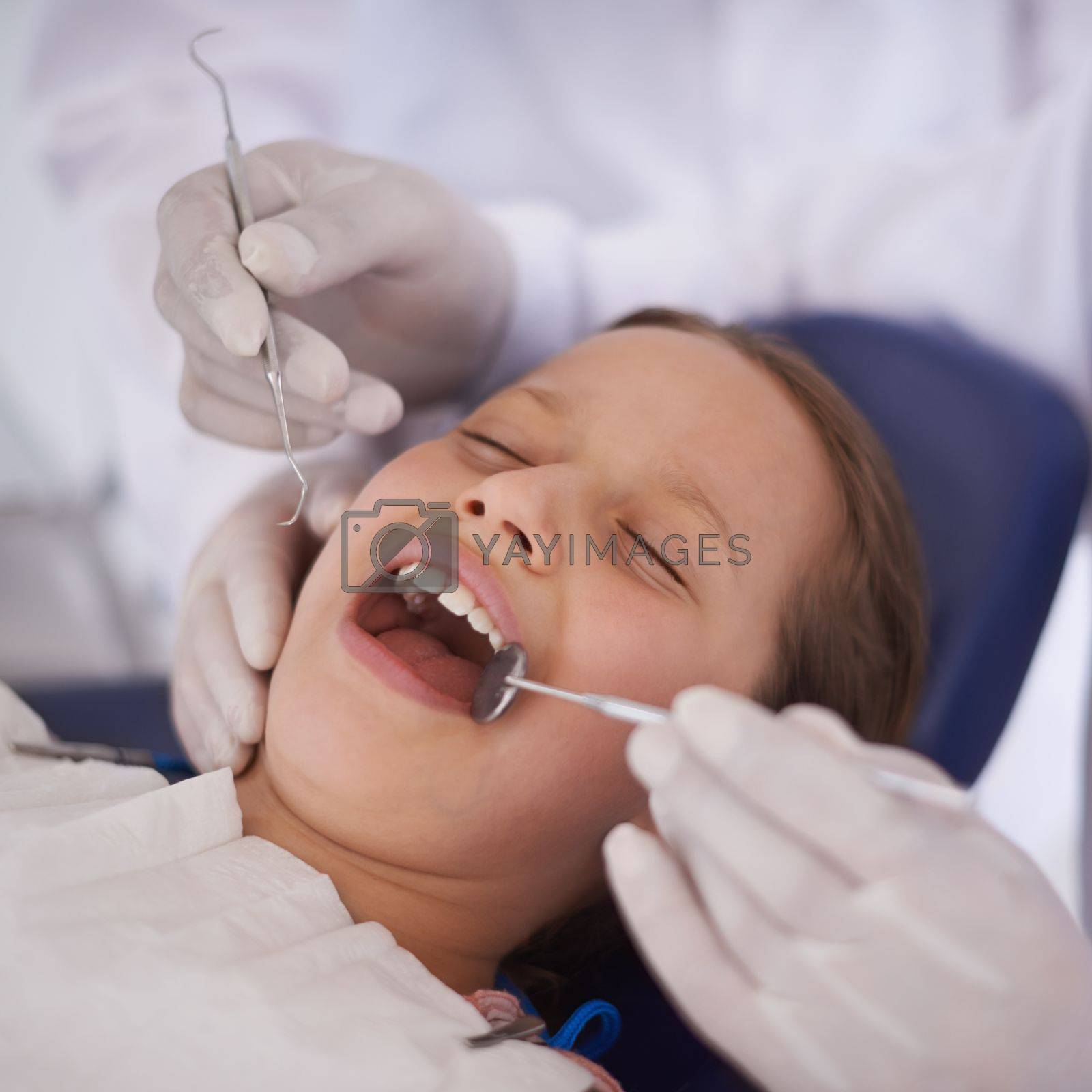 Royalty free image of Everything seems to be in order. A dentist performing a dental examination of a little girls teeth. by YuriArcurs
