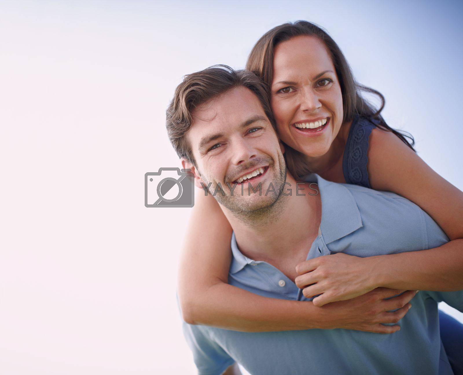 Royalty free image of Keeping the romance alive. A handsome man piggybacking his loving wife outdoors. by YuriArcurs