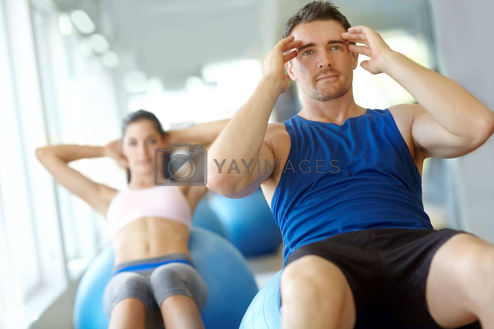 Royalty free image of Feeling energized. Two people doing exercises on Swiss balls at the gym. by YuriArcurs