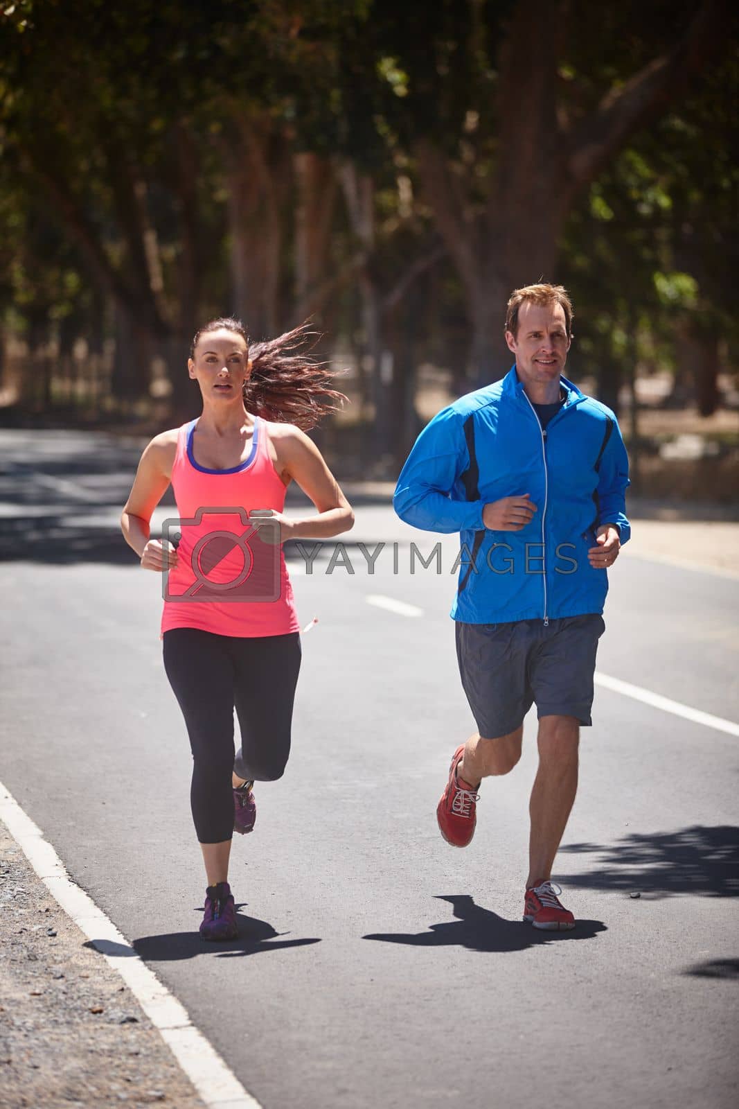Royalty free image of Hitting the streets. Full length shot of a couple jogging on a road. by YuriArcurs