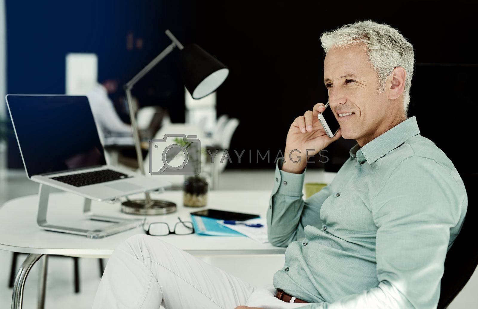 Royalty free image of Communication is key to his business. a mature businessman working at his desk in an office. by YuriArcurs