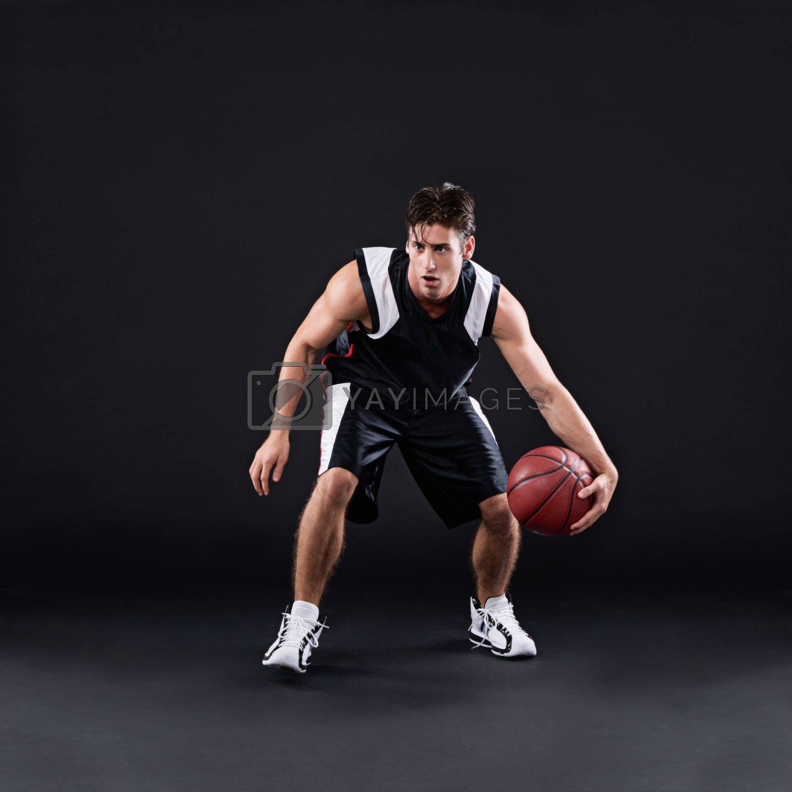 Royalty free image of Dribbling pro. Full length shot of a male basketball player in action against a black background. by YuriArcurs