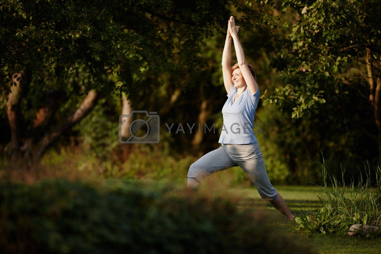 Royalty free image of Yoga keeps her glowing. an attractive woman doing yoga in the outdoors. by YuriArcurs