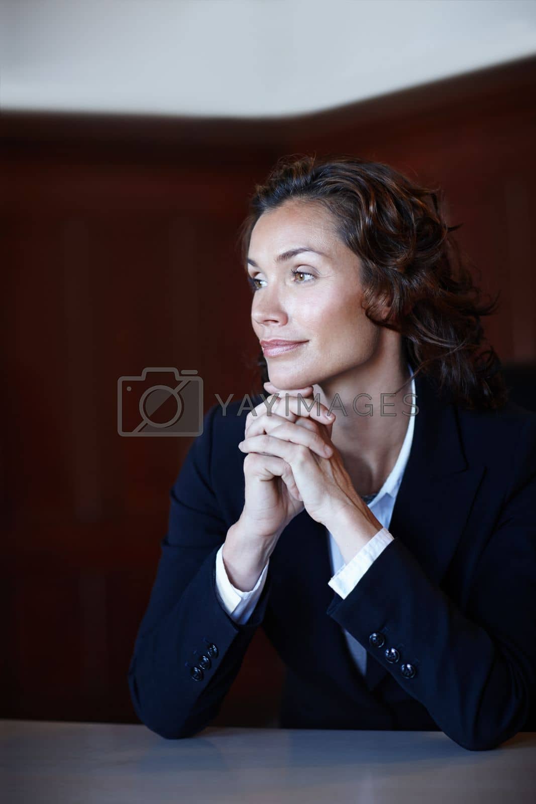 Royalty free image of Thinking about her court case. Mature legal woman looking away from the camera while sitting with her hands clasped. by YuriArcurs