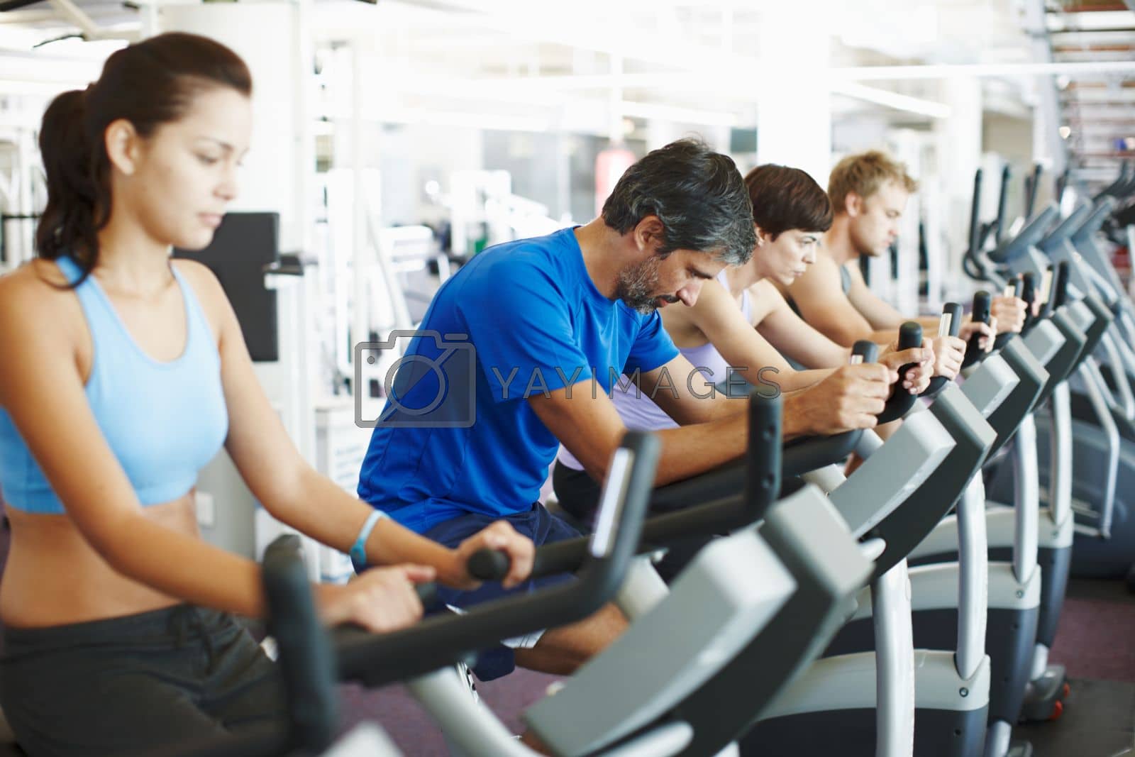 Royalty free image of The warm down. a row of people working out on the exercise bikes at the gym. by YuriArcurs