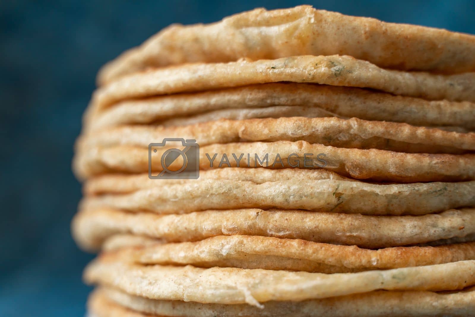 Royalty free image of Flatbread lavash, chapati, naan, heap of tortilla on a blue background Homemade flatbread stacked. by Matiunina