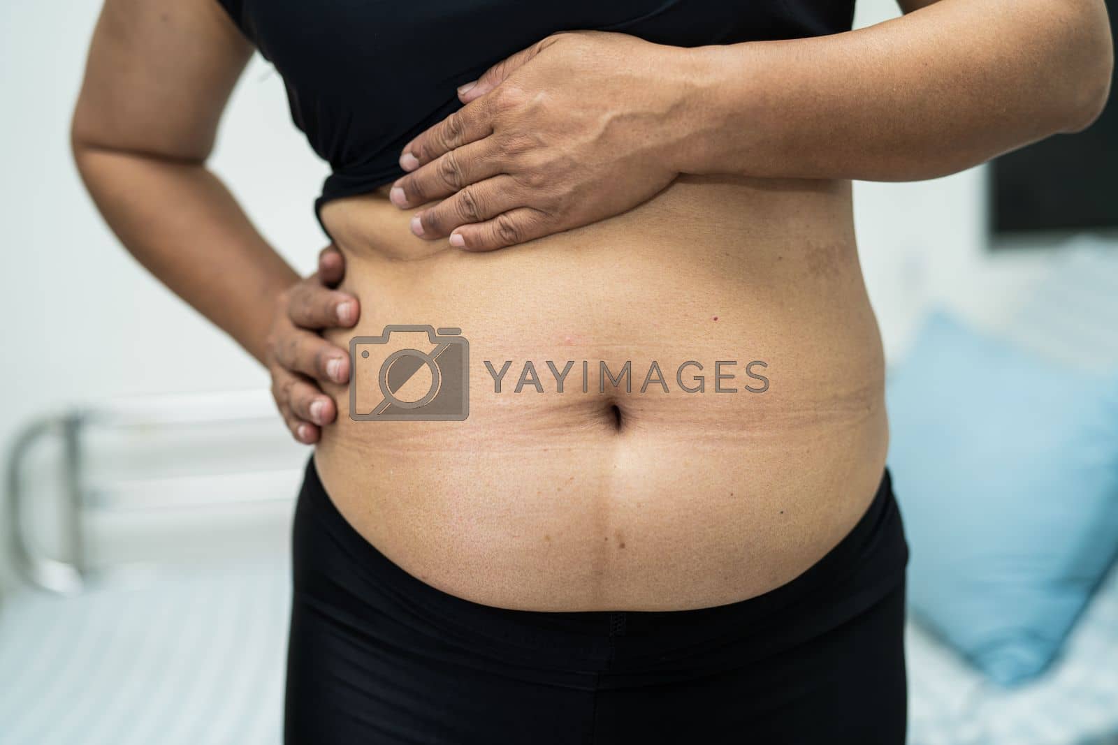 Royalty free image of Overweight Asian woman show fat belly at office. by pamai
