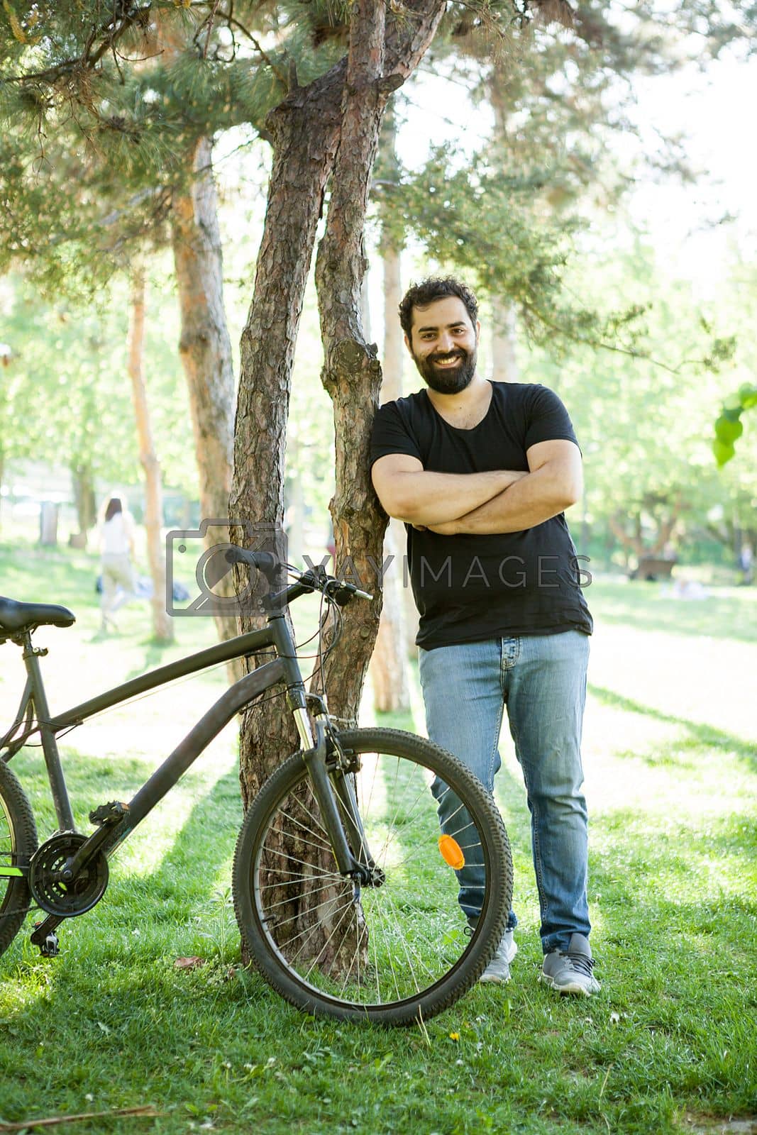 Royalty free image of Smiling bearded man leaning on a tree in the park by DCStudio