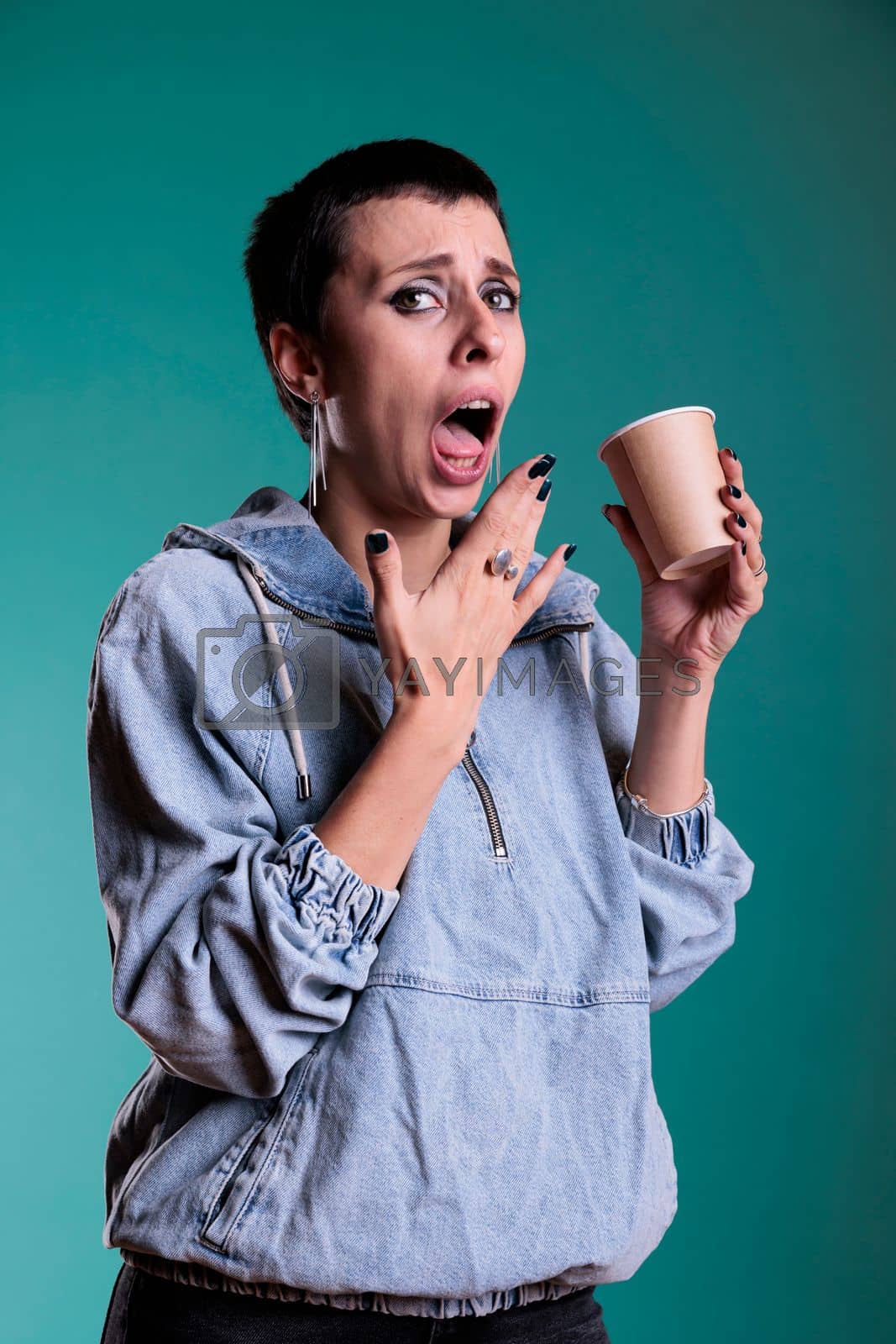 Royalty free image of Woman burned her tongue after tasting too hot coffee during leisure time in studio by DCStudio