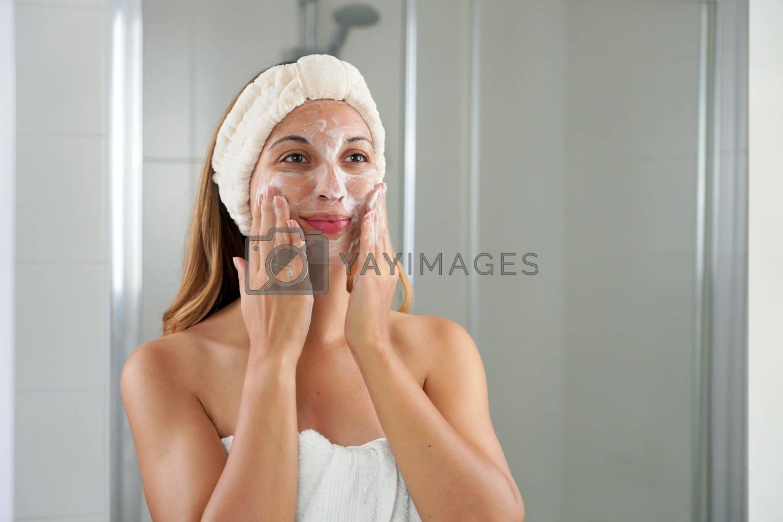 Royalty free image of Skincare woman washing face foaming soap scrubbing skin. Face wash exfoliation scrub soap woman washing scrubbing with skincare cleansing product. Enjoying relaxing time. by sergio_monti