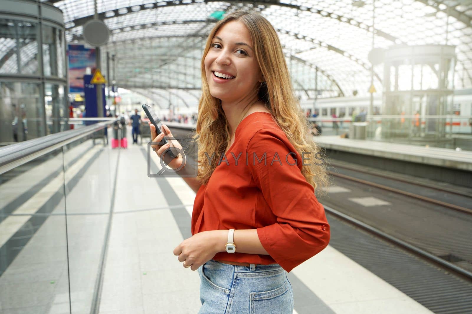 Royalty free image of Attractive hispanic girl in train station looking at camera holding phone by sergio_monti